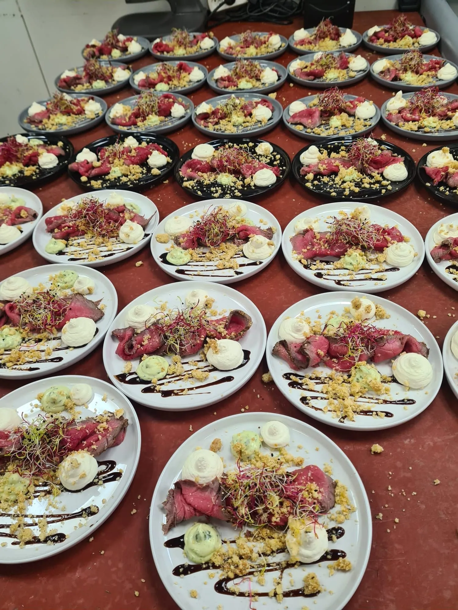 Assiettes de bœuf dressées en série en cuisine pour un repas de groupe.